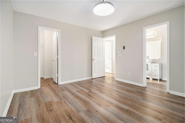 unfurnished bedroom featuring light hardwood / wood-style flooring, a walk in closet, and a closet