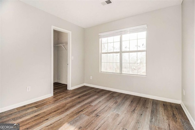 unfurnished bedroom featuring dark hardwood / wood-style flooring, a spacious closet, and a closet