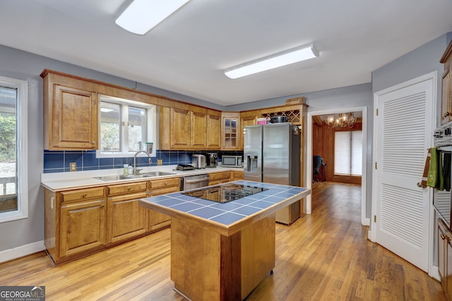 kitchen with sink, tile countertops, a center island, light hardwood / wood-style flooring, and appliances with stainless steel finishes