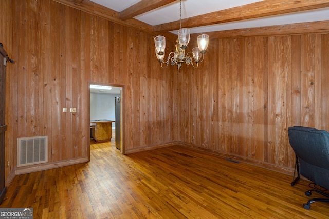 unfurnished office with wooden walls, wood-type flooring, beam ceiling, and a chandelier