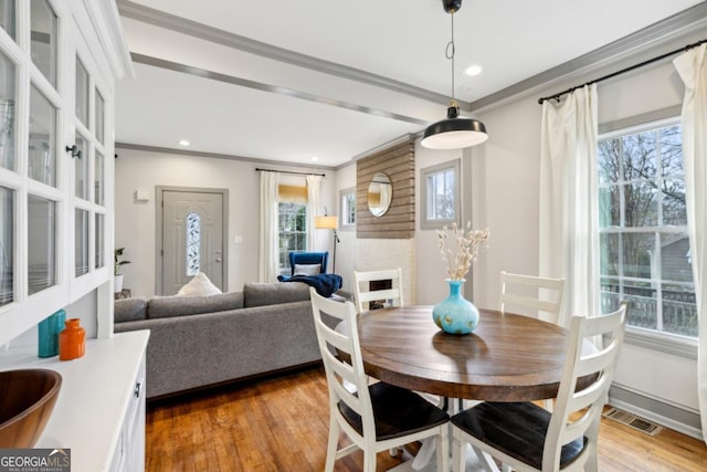 dining room featuring crown molding, a healthy amount of sunlight, and hardwood / wood-style floors