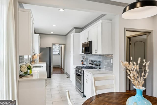 kitchen with white cabinetry, appliances with stainless steel finishes, ornamental molding, and decorative backsplash