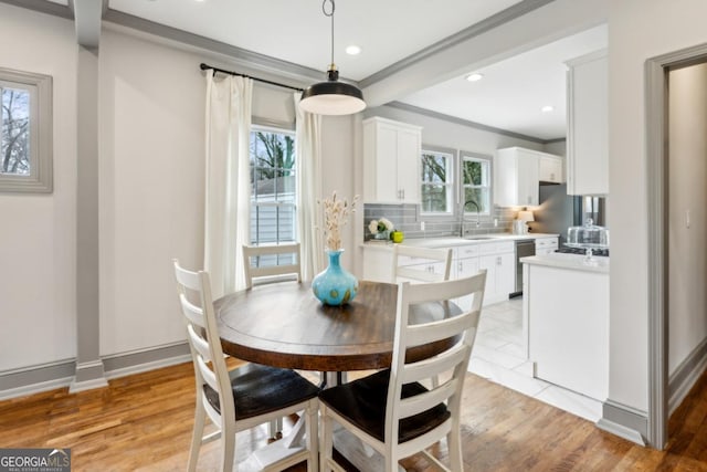 dining space with crown molding, sink, and light hardwood / wood-style floors