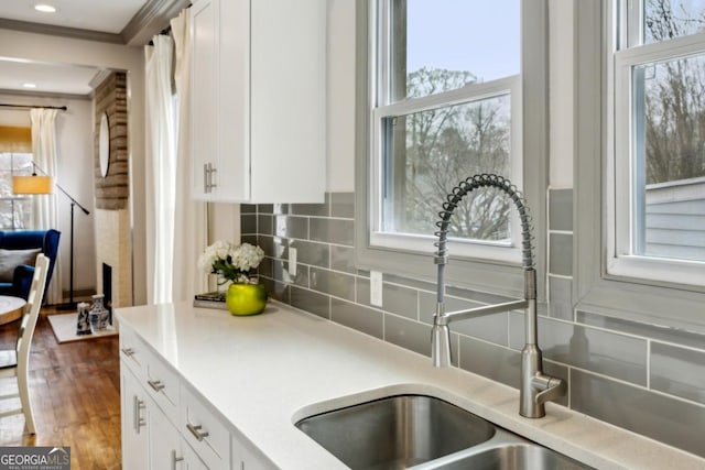 kitchen with sink, decorative backsplash, wood-type flooring, and white cabinets