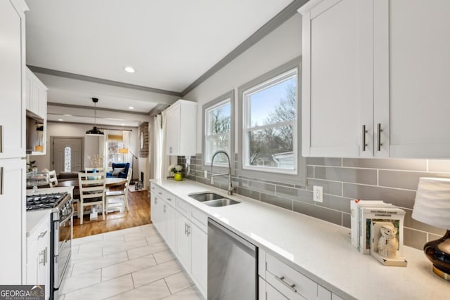 kitchen with sink, appliances with stainless steel finishes, white cabinets, pendant lighting, and backsplash