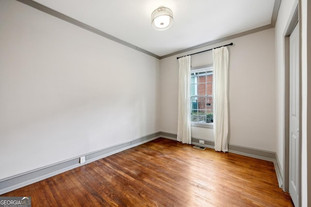 unfurnished room with hardwood / wood-style flooring and ornamental molding