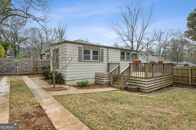 rear view of house with a wooden deck and a lawn