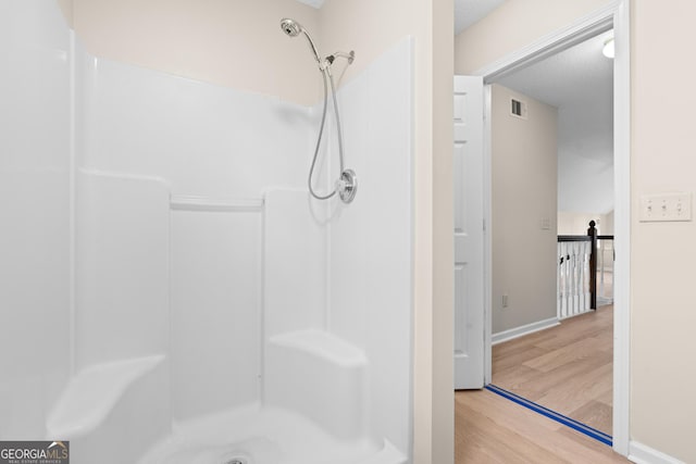 bathroom featuring hardwood / wood-style floors, a textured ceiling, and a shower