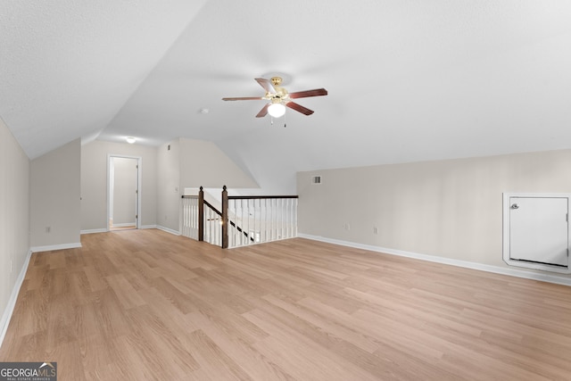 additional living space with lofted ceiling, a textured ceiling, light hardwood / wood-style floors, and ceiling fan