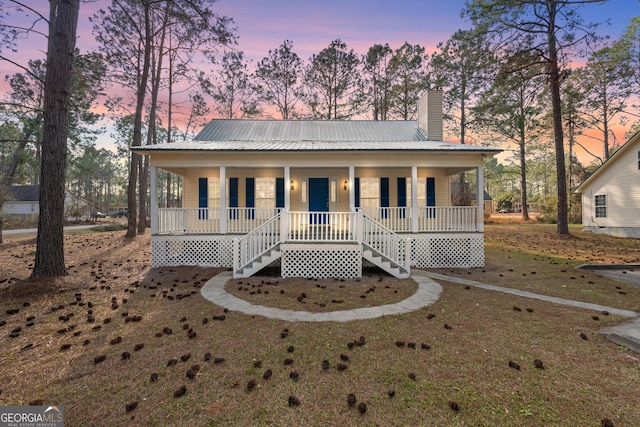 view of front of property with covered porch and a lawn