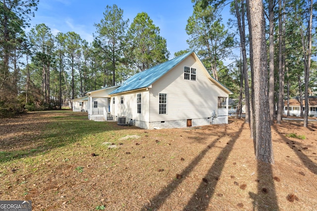 view of side of home featuring covered porch, a lawn, and central air condition unit