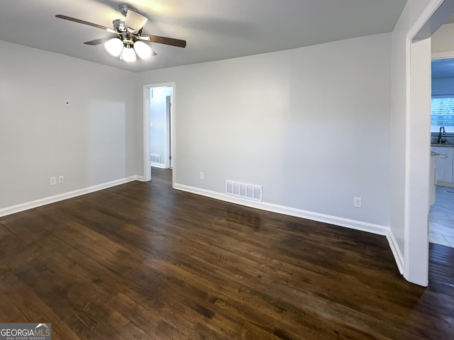 empty room with dark hardwood / wood-style flooring and ceiling fan