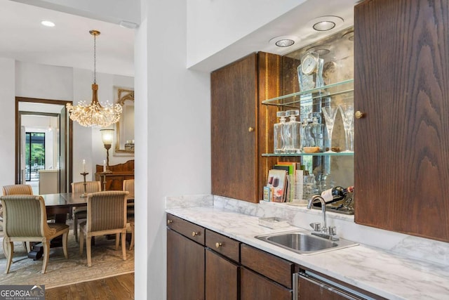 kitchen featuring sink, dishwasher, dark brown cabinets, dark hardwood / wood-style floors, and decorative light fixtures