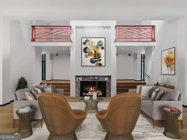 sitting room with wood finished floors, a premium fireplace, and stairs
