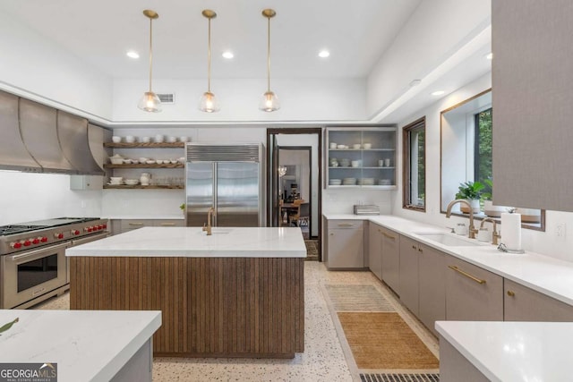 kitchen featuring high end appliances, sink, decorative light fixtures, and a kitchen island