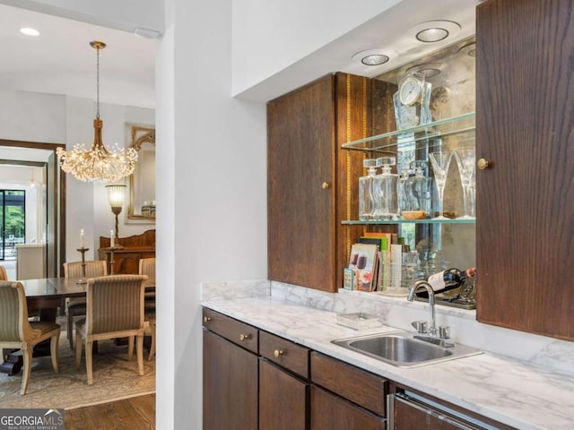 bar featuring a sink, pendant lighting, a notable chandelier, and dark wood-style floors