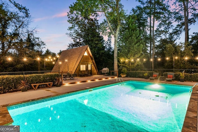 pool at dusk featuring a patio area