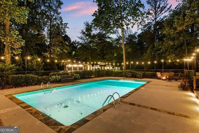 pool at dusk featuring a patio