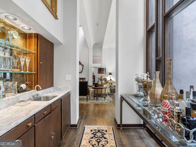 bar with a sink, baseboards, indoor bar, and dark wood-style floors