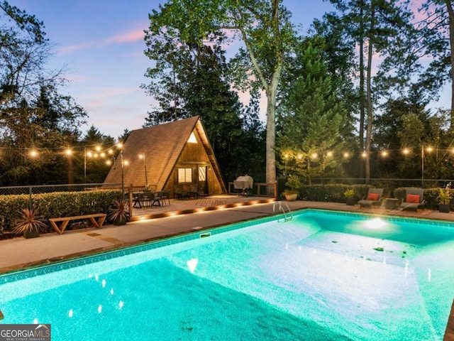 view of pool with a patio area, an outbuilding, a fenced in pool, and fence