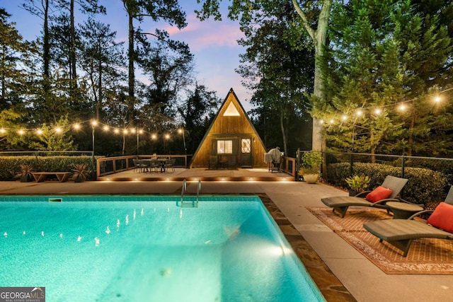 pool at dusk with a patio area