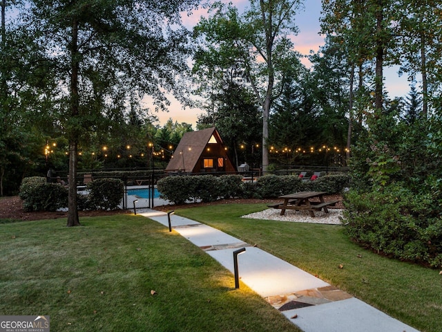 view of home's community with fence, a lawn, and a swimming pool