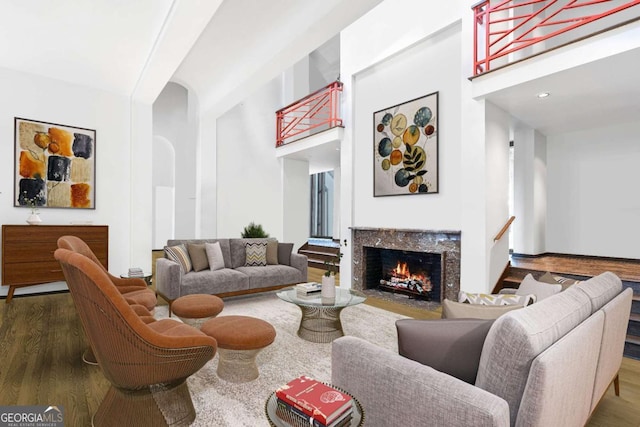 living room featuring a high ceiling, a premium fireplace, and hardwood / wood-style floors