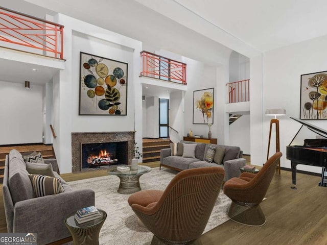 living room featuring stairs, a fireplace, a high ceiling, and wood finished floors