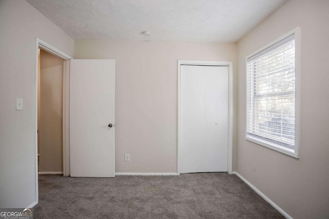 unfurnished bedroom featuring carpet flooring, a textured ceiling, and a closet