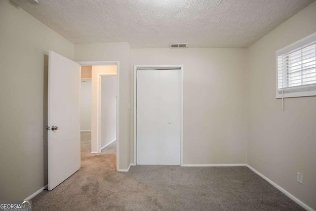 unfurnished bedroom featuring a closet, a textured ceiling, and carpet