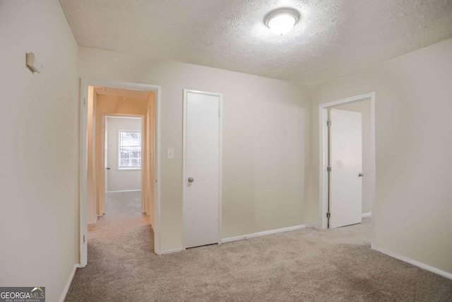 spare room with light carpet and a textured ceiling