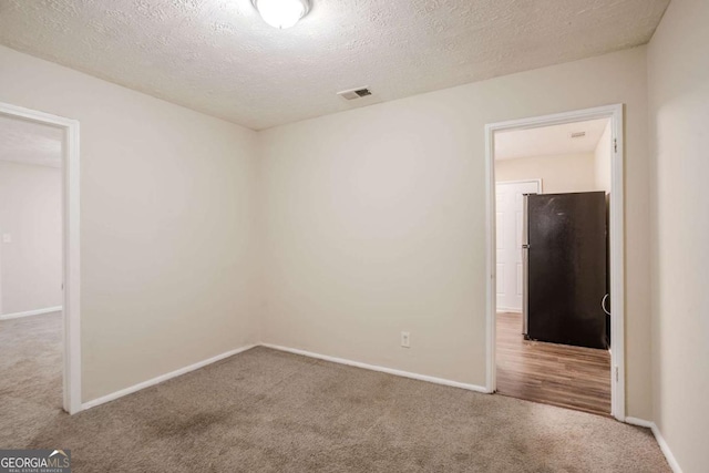 carpeted spare room featuring a textured ceiling