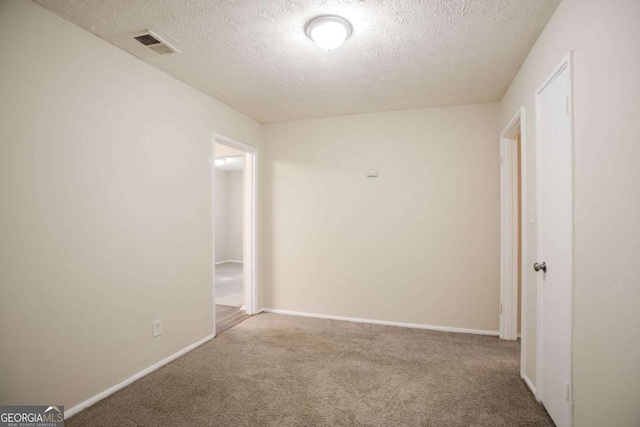 spare room featuring carpet flooring and a textured ceiling