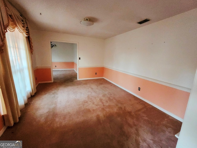 empty room featuring baseboards, visible vents, and carpet flooring