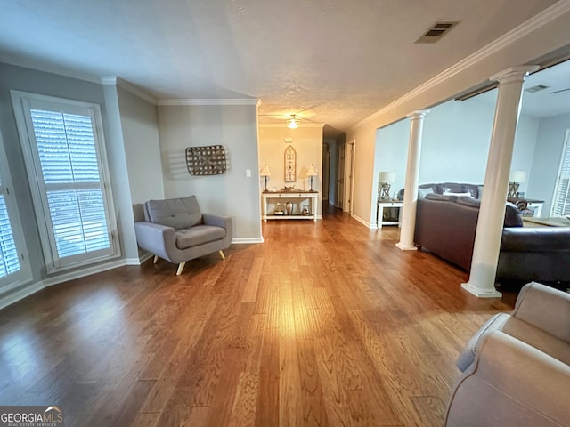 sitting room featuring ornate columns, ornamental molding, and hardwood / wood-style flooring