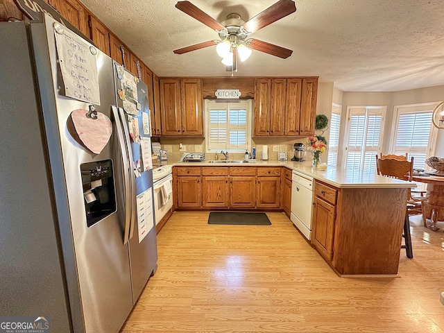 kitchen with sink, a breakfast bar area, light wood-type flooring, kitchen peninsula, and dishwasher