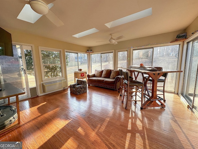 sunroom with a skylight, an AC wall unit, and ceiling fan