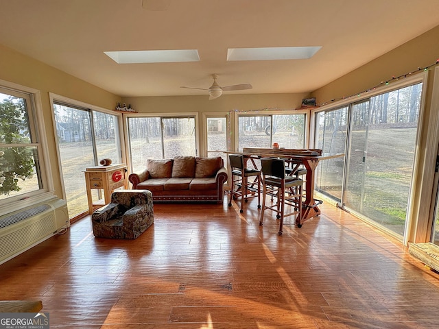 sunroom featuring ceiling fan, a skylight, and an AC wall unit