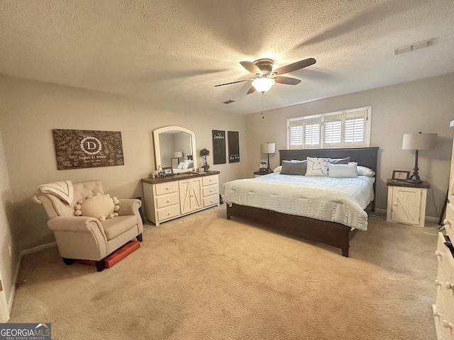 bedroom featuring a textured ceiling, light colored carpet, and ceiling fan