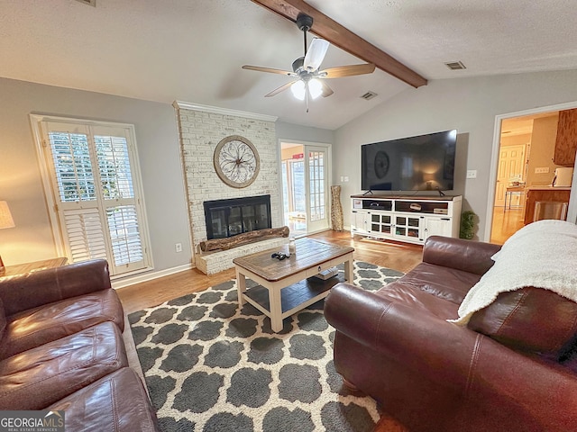 living room featuring vaulted ceiling with beams, light hardwood / wood-style flooring, a healthy amount of sunlight, and a brick fireplace