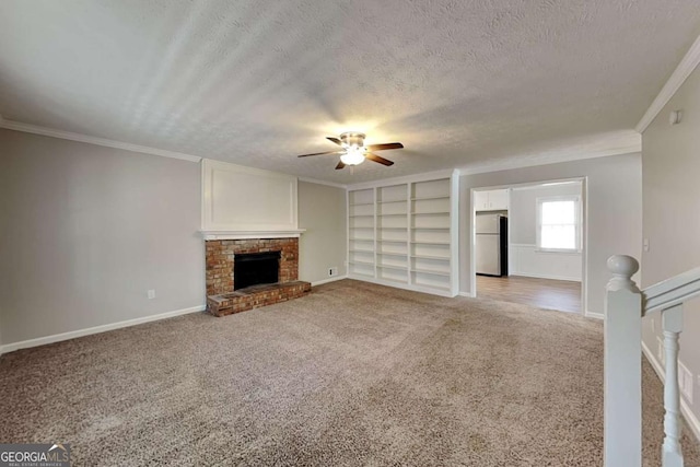 unfurnished living room with crown molding, a textured ceiling, a brick fireplace, built in shelves, and light colored carpet