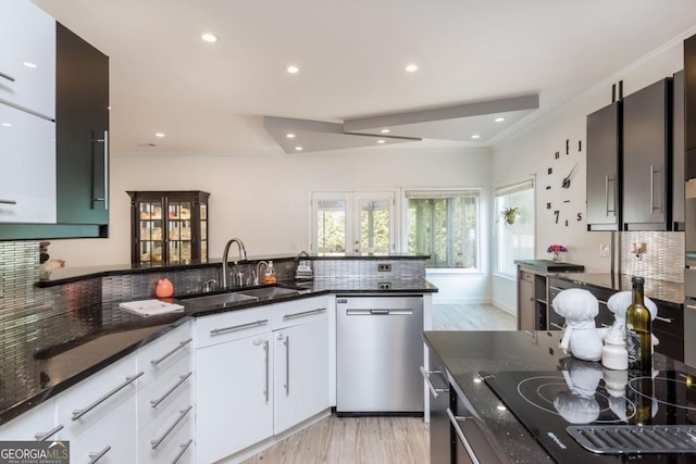 kitchen with white cabinetry, sink, stainless steel dishwasher, and dark stone countertops