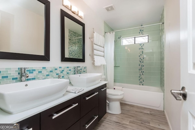 full bathroom with shower / tub combo, hardwood / wood-style floors, backsplash, vanity, and toilet