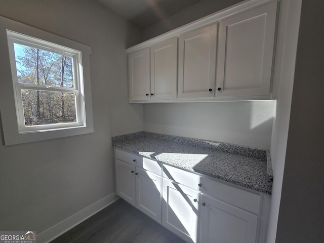 kitchen with white cabinetry, dark wood-type flooring, and light stone countertops