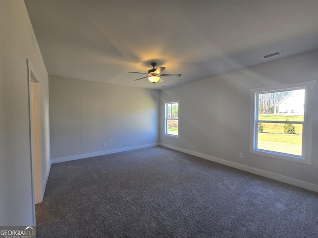 unfurnished room with dark colored carpet and ceiling fan