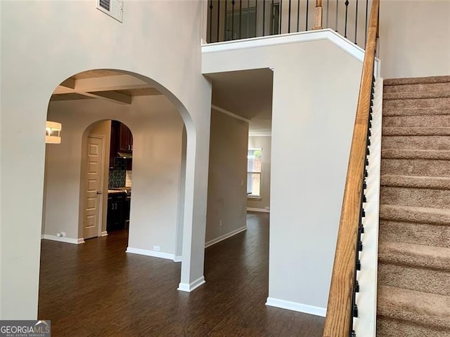 stairs with a towering ceiling and hardwood / wood-style floors