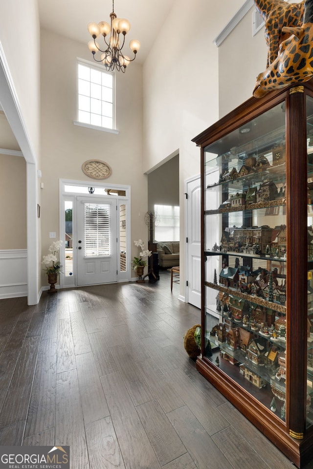 foyer featuring an inviting chandelier, a towering ceiling, and dark hardwood / wood-style floors