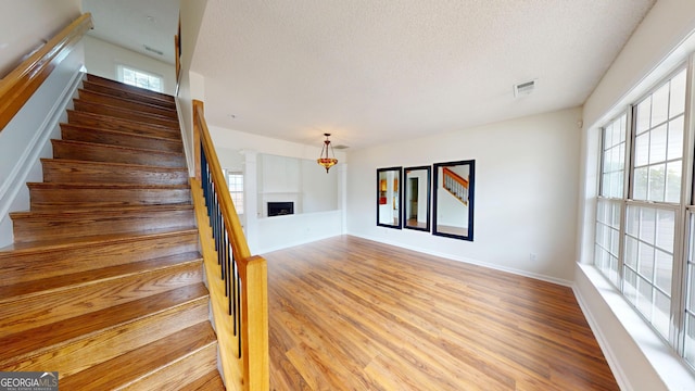 stairway with hardwood / wood-style floors and a textured ceiling