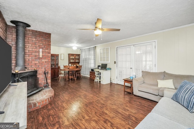 living room with ceiling fan, a wood stove, a textured ceiling, and dark hardwood / wood-style flooring