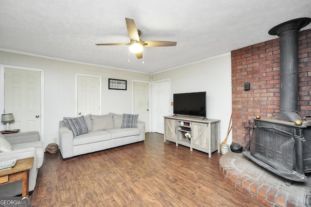 living room featuring dark wood-type flooring, ceiling fan, a textured ceiling, and a wood stove